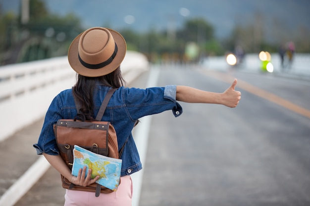 Foto grátis viajantes do sexo feminino que acenam carros na estrada