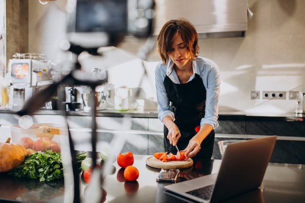 Videoblogger jovem cozinhar na cozinha e filmar