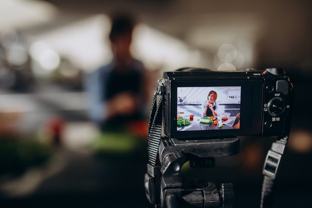 Foto grátis videoblogger jovem cozinhar na cozinha e filmar