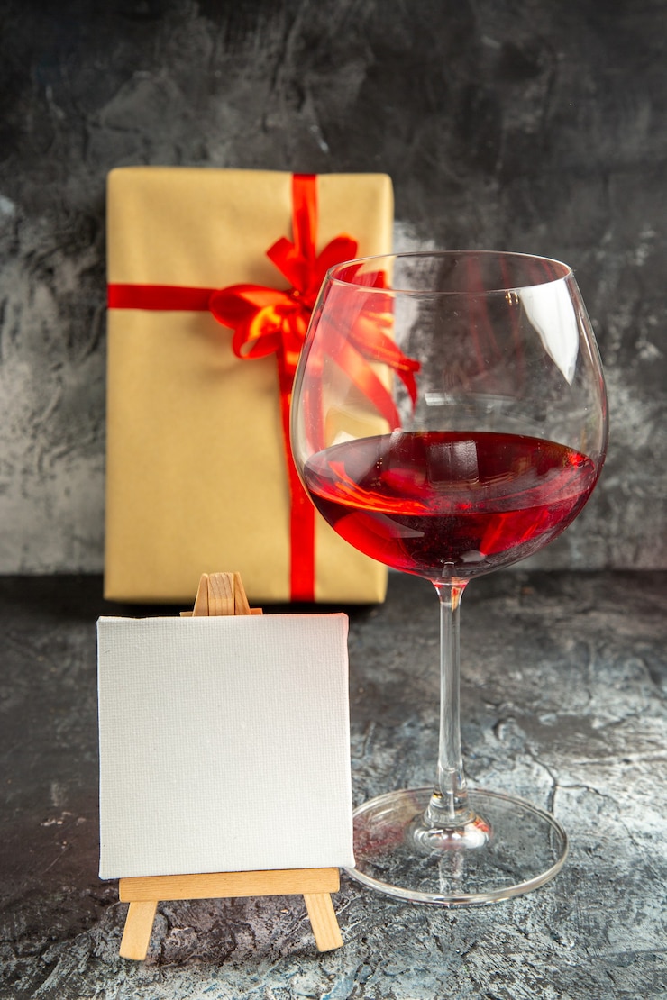 Foto grátis vidro de vista frontal de tela branca de vinho presente de natal em cavalete de madeira no escuro