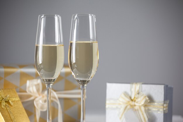 Vidros com champanhe e presentes de fundo