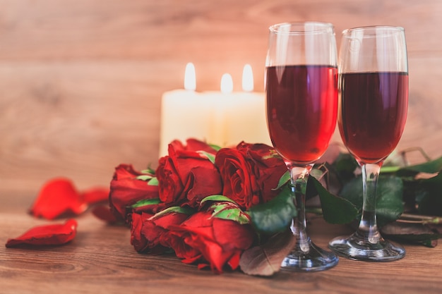 Vidros de vinho com velas acesas e um buquê de rosas