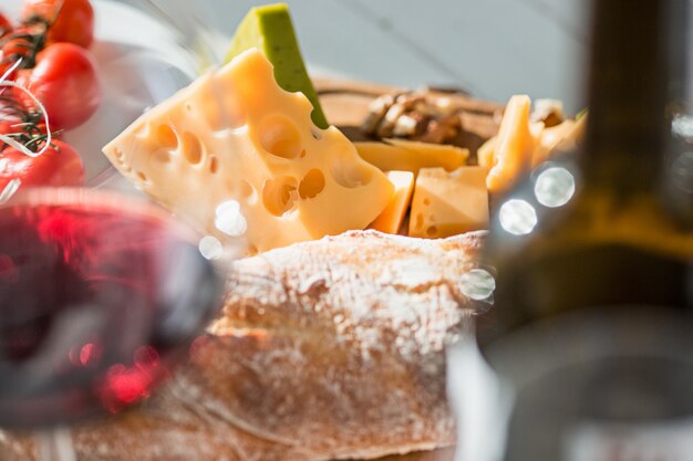 Vinho, baguete e queijo na mesa de madeira