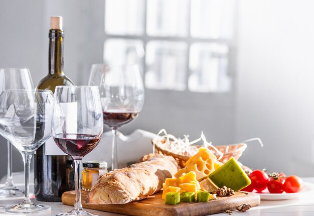 Vinho, baguete e queijo na mesa de madeira