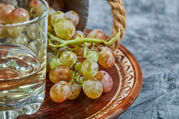 Vinho branco em um copo com um cacho de uvas verdes ao redor.