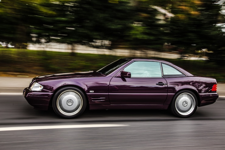 Foto grátis vintage bordeaux sedan carro dirigindo na estrada, vista lateral.