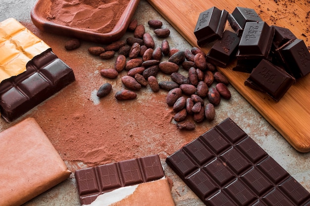 Visão aérea de barras de chocolate com cacau em pó e feijão cru