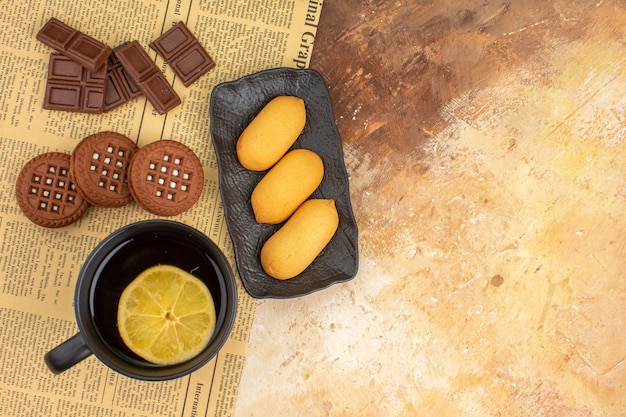 Visão aérea de três biscoitos e chá em uma xícara preta na mesa de cores diferentes