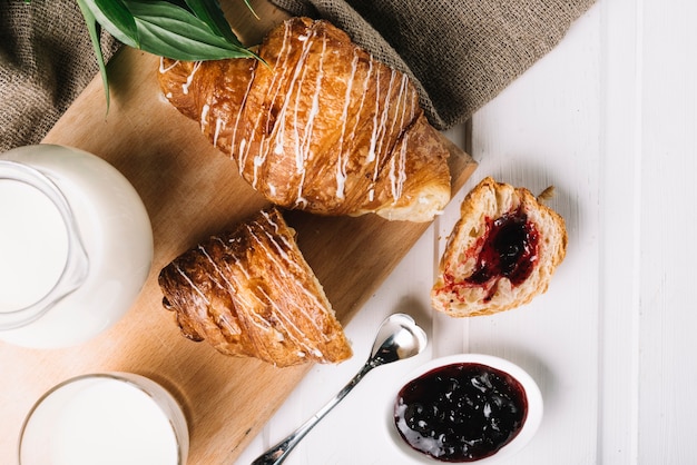 Visão aérea do croissant com geléia de frutas e leite na mesa branca