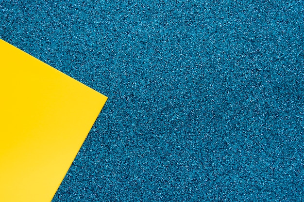 Visão aérea do papel cartão amarelo na superfície azul