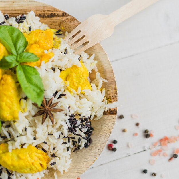 Visão aérea do saboroso frango e arroz no prato com folhas de manjericão