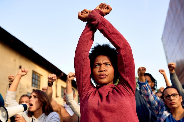 Visão de ângulo baixo de mulher afro-americana com gesto de cruzar o braço participando de um protesto pelos direitos humanos