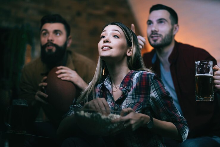 Foto grátis visão de baixo ângulo de fãs do esporte assistindo jogo na tv em casa o foco está na mulher com pipoca