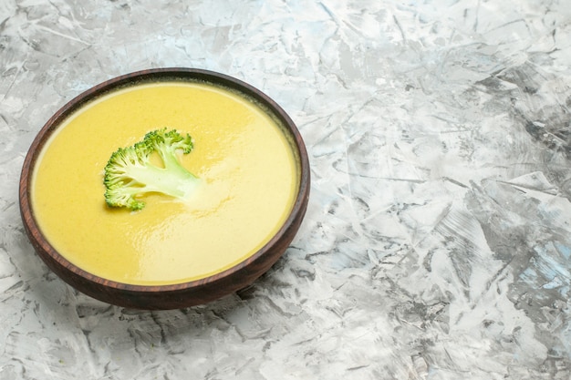 Visão horizontal de sopa cremosa de brócolis em uma tigela marrom na mesa cinza
