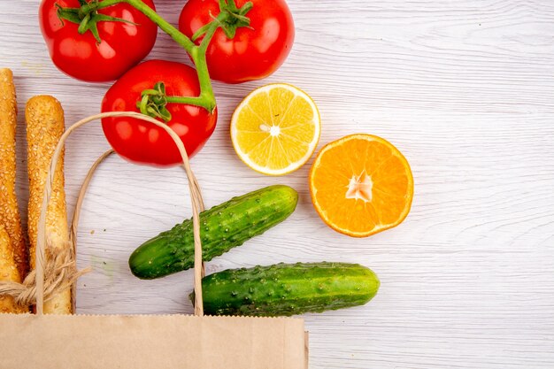 Visão horizontal de tomates frescos com pepino caule de limão no fundo branco