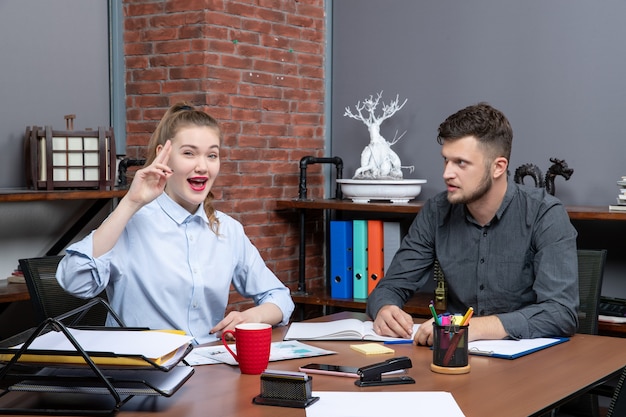 Visão superior de trabalhadores qualificados positivos e motivados fazendo um brainstorming sobre uma questão importante no escritório