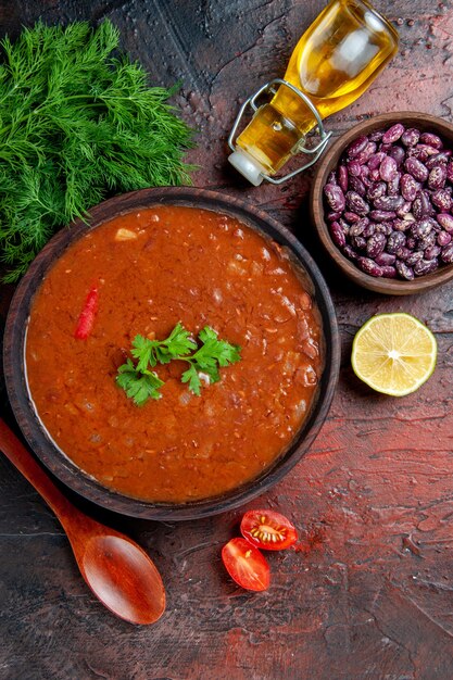 Visão vertical da clássica sopa de tomate em uma tigela de feijão marrom e colher uma garrafa de óleo