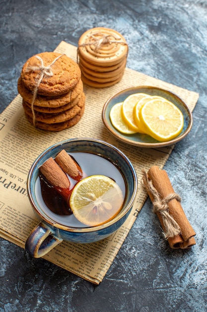 Visão vertical da hora do chá com deliciosos biscoitos de canela e limão empilhados em um jornal velho sobre fundo escuro