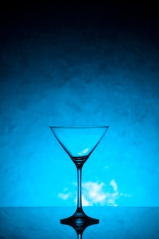 Visão vertical da taça de vidro para vinho em pé sobre fundo azul