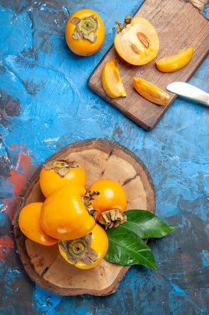 Foto grátis visão vertical de deliciosos diospyros kaki inteiros e cortados