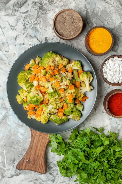 Foto grátis visão vertical de especiarias diferentes de salada de vegetais saudáveis e um monte de verde na mesa branca