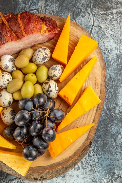 Visão vertical de um lanche delicioso, incluindo frutas e alimentos para vinho em uma bandeja marrom em fundo cinza