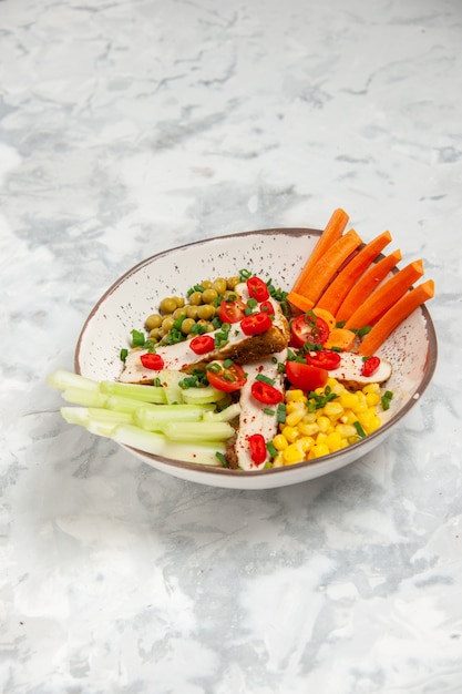 Visão vertical de uma deliciosa salada com vários ingredientes em um prato na superfície branca