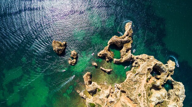 Vista aérea da cênica Ponta da Piedade de Lagos, Portugal. Falésias íngremes à beira-mar e águas do oceano azul na região do Algarve em Portugal