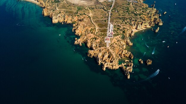 Vista aérea da Ponta da Piedade de Lagos, Portugal. Bela paisagem de falésias íngremes à beira-mar e águas do oceano azul na região do Algarve em Portugal