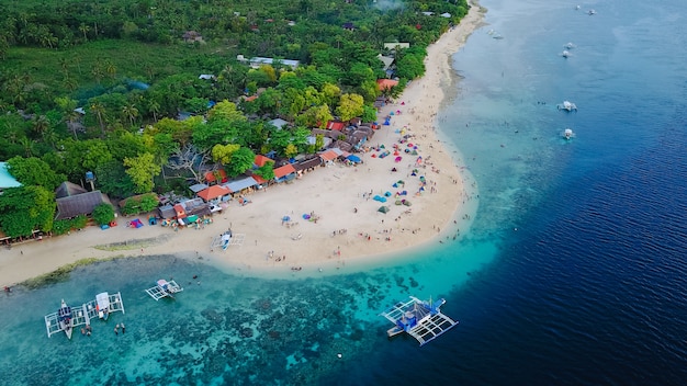 Vista aérea da praia de areia com turistas que nadam na linda água do mar clara da ilha de Sumilon, pousando na praia perto de Oslob, Cebu, Filipinas. - Impulse o processamento de cores.