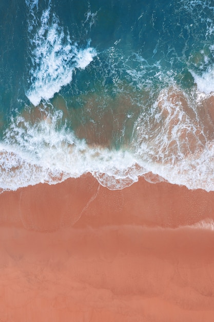 Vista aérea da praia rosa e da onda do oceano azul.