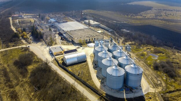 Vista aérea de drone de cisternas de metal de uma vinícola com árvores nuas e campos ao redor na Moldávia