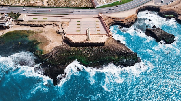 Foto grátis vista aérea de drones da costa rochosa do oceano atlântico de rabat marrocos com farol de água azul