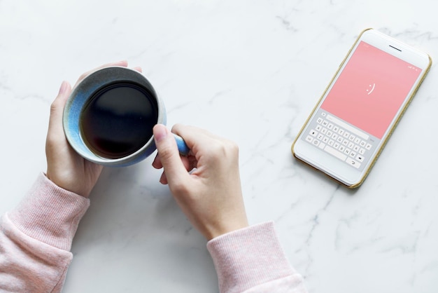 Vista aérea, de, mulher, com, um, xícara quente, de, café, e, um, smartphone