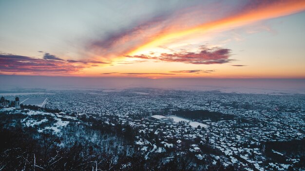 Vista aérea de um cenário deslumbrante do pôr do sol sobre a cidade coberta de neve no inverno