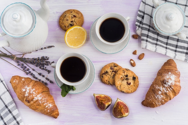 Foto grátis vista aérea do bule; biscoitos; café; croissant; fig; e limão na mesa