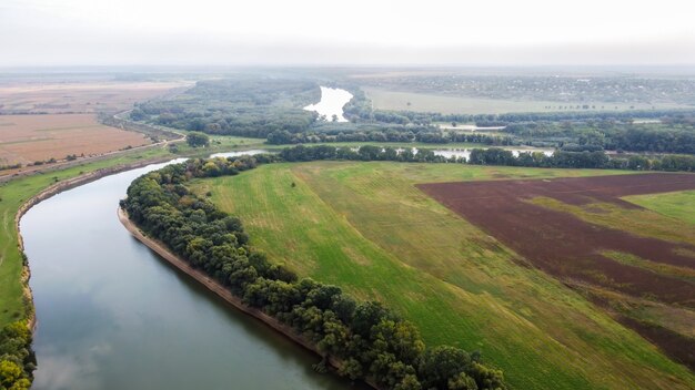 Vista aérea do drone da natureza na Moldávia, rio flutuante com o céu refletido, campos verdes com árvores, névoa no ar