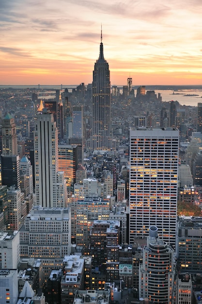 Vista aérea do horizonte de nova york ao pôr do sol com nuvens coloridas e arranha-céus do centro de manhattan.