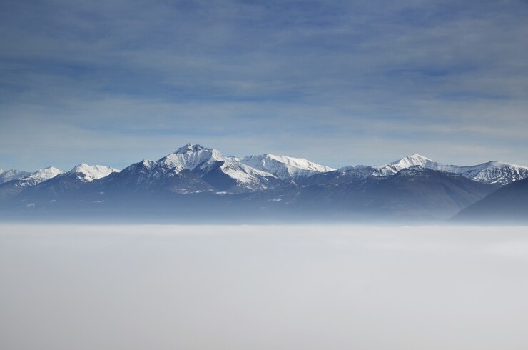 Foto grátis vista aérea incrível de montanhas parcialmente cobertas de neve e posicionadas acima das nuvens