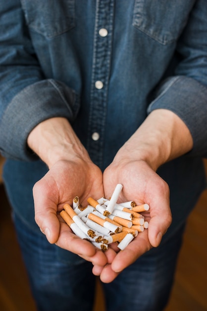 Vista alta ângulo, de, cigarros quebrados, em, mão homem