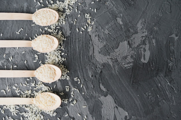 Foto grátis vista alta ângulo, de, concreto, superfície, com, arroz branco, em, pequeno, colher madeira