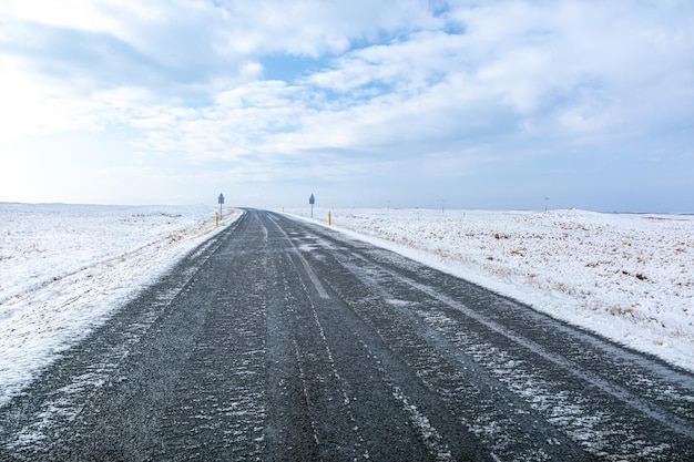 Vista arrepiante de uma estrada não pavimentada entre campos cobertos de neve na Islândia