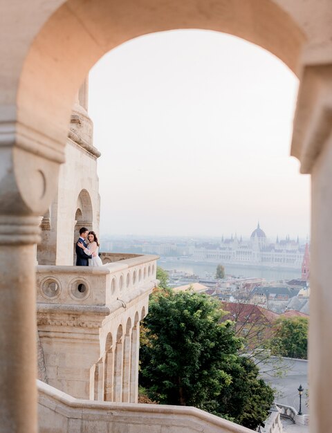 Vista através do arco de pedra da cidade de Budapeste e uma pequena silhueta de um casal apaixonado