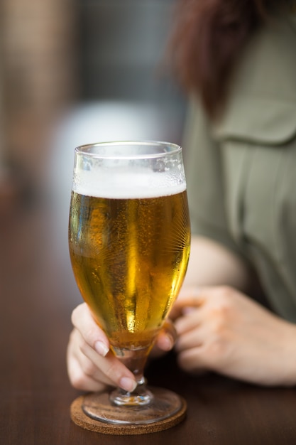 Vista colhida da mulher segurando copo de cerveja
