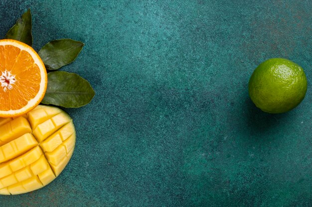 vista cópia espaço em fatias de manga com metade de uma laranja e banana em uma mesa verde
