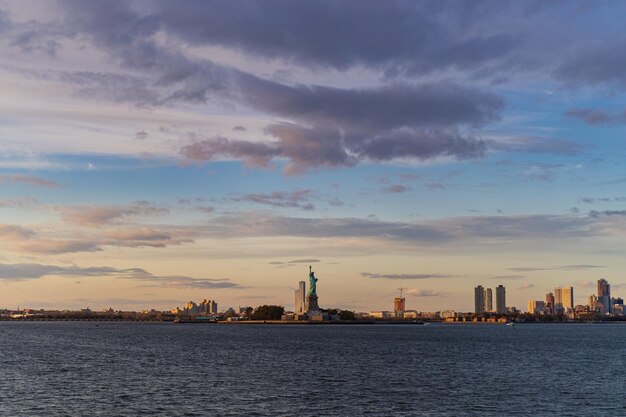 Vista da Estátua da Liberdade da água ao pôr do sol, Nova York, EUA