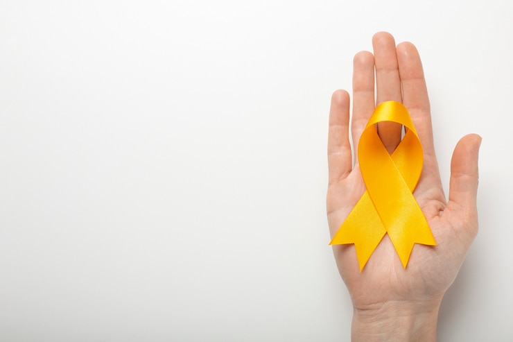 Mão de pessoa branca segurando o laço amarelo, símbolo da campanha do setembro amarelo. A síndrome de Burnout também pode ser abordada durante esse mês em empresas.