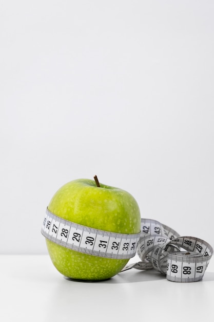 Foto grátis vista da fita métrica com fruta maçã