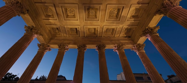 Vista da Maison Carree pelo templo raman noturno em Nimes