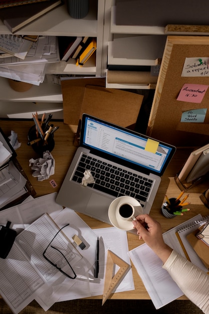 Vista da mesa de escritório com espaço de trabalho bagunçado e laptop